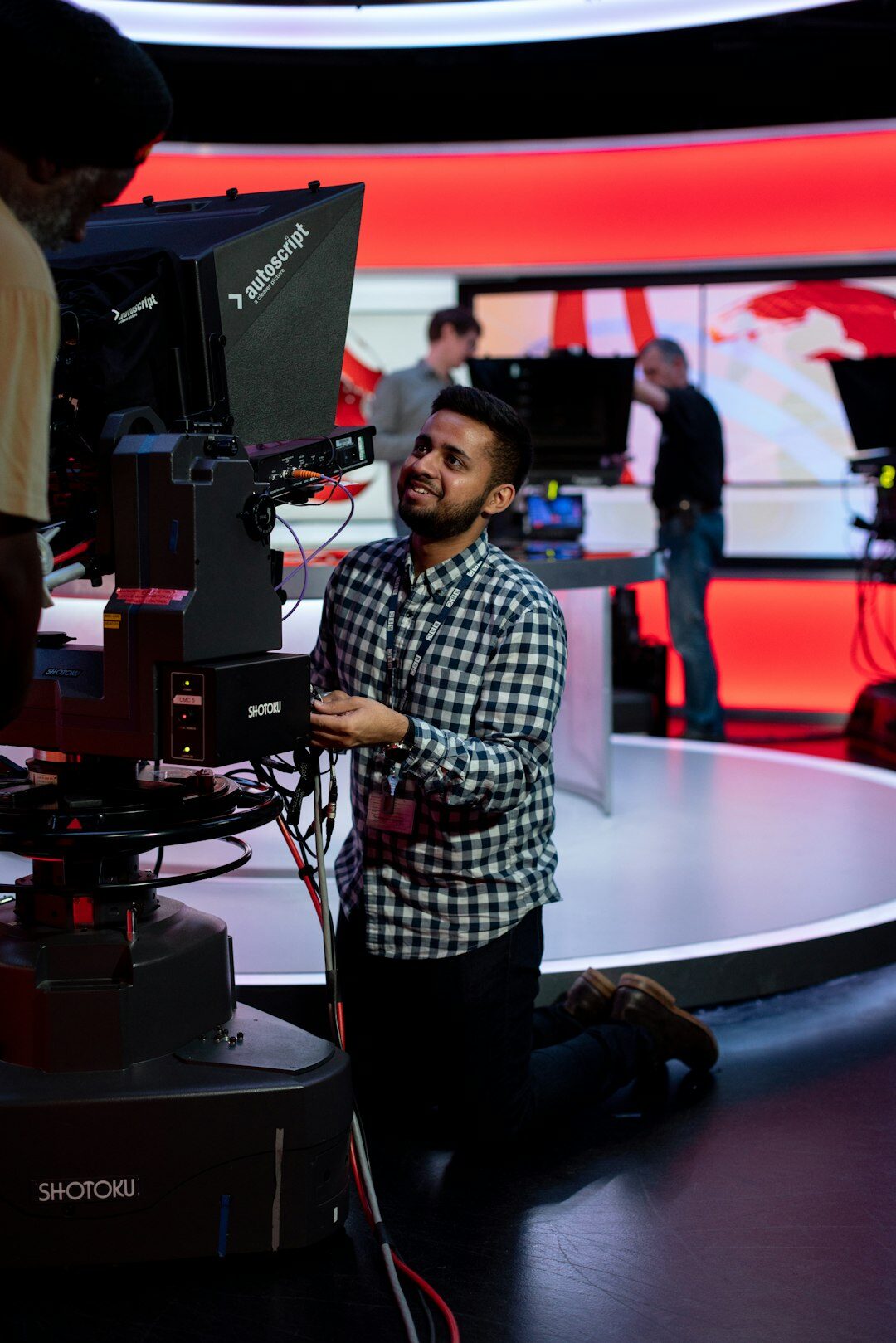 Television studio camera pointed at a presenter's desk